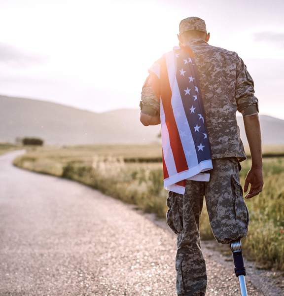 Rear View Of Young Amputee Soldier Walking Road Wearing American Flag
